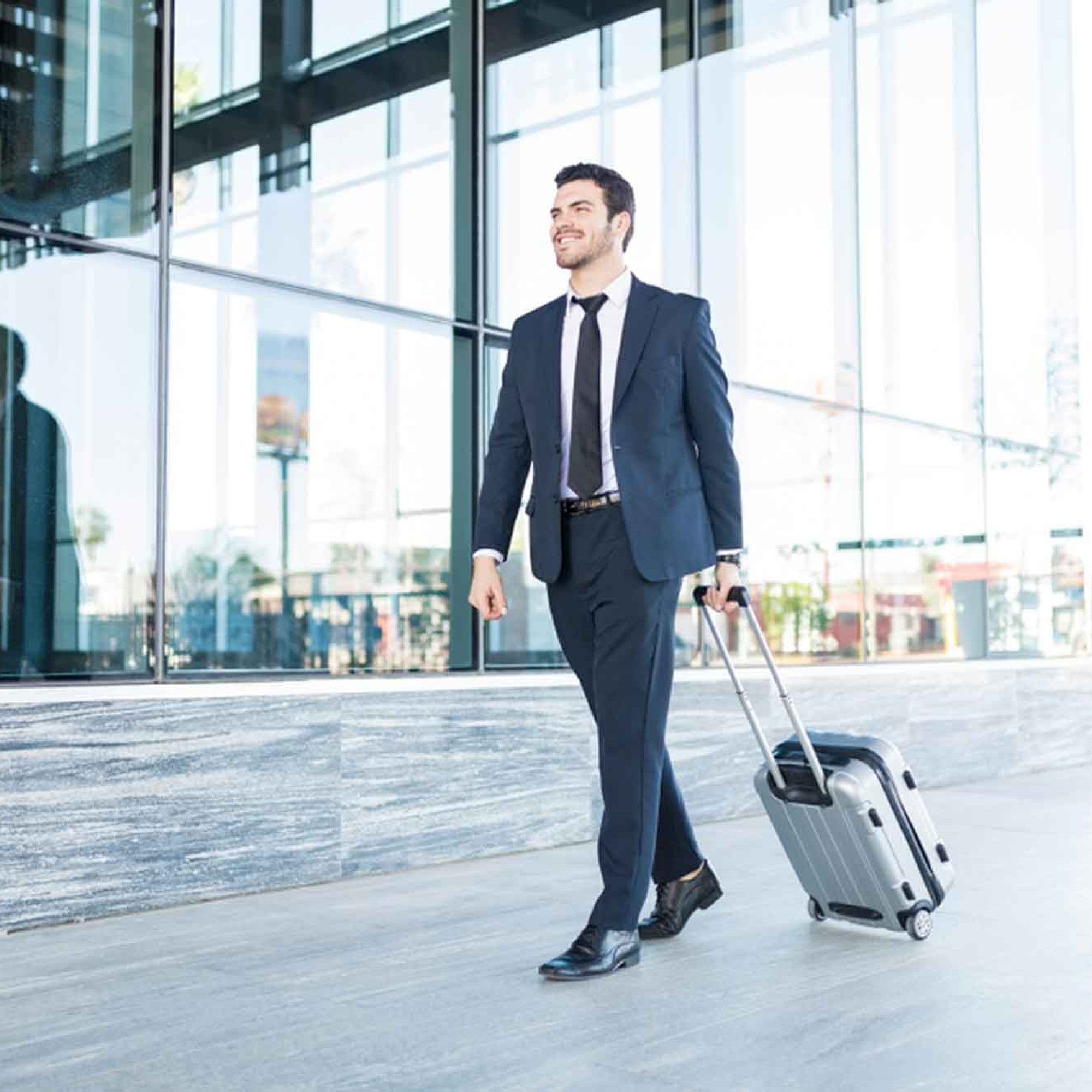 Junger Mann im Anzug mit Koffer auf Businessreise