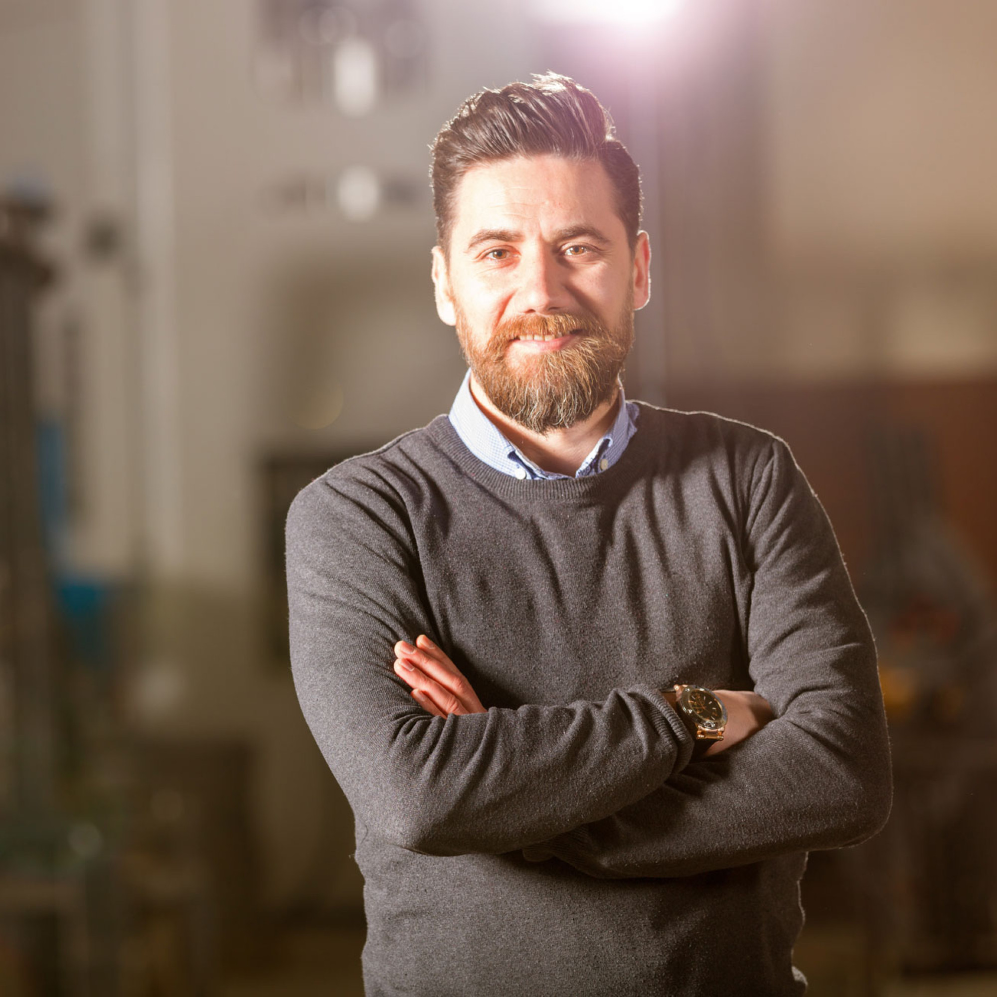 Mann mit braunem Pullover schaut in die Kamera