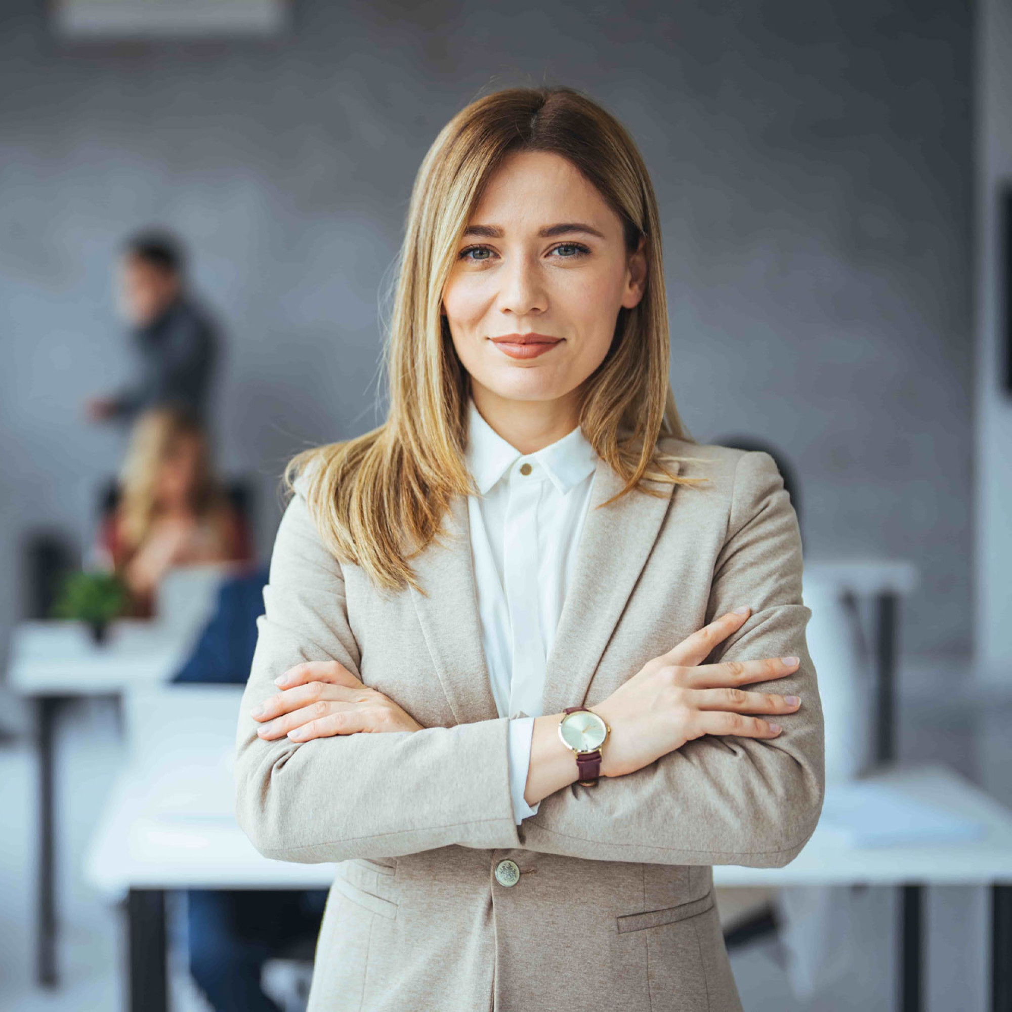 Junge Frau in beigem Blazer schaut in die Kamera