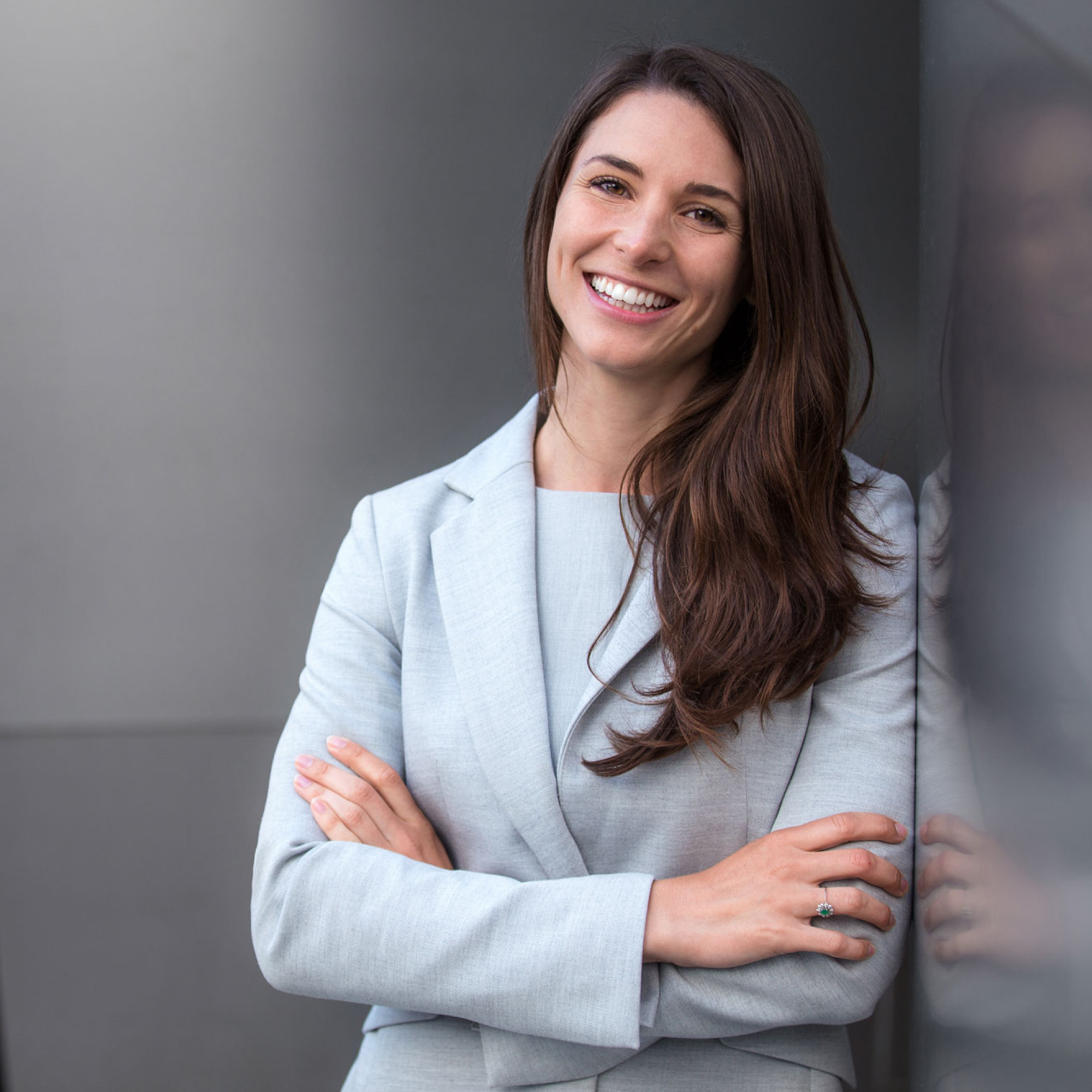 Dunkelhaarige Studentin des MBA Fernstudiums Finance lächelt im hellen Business Outfit