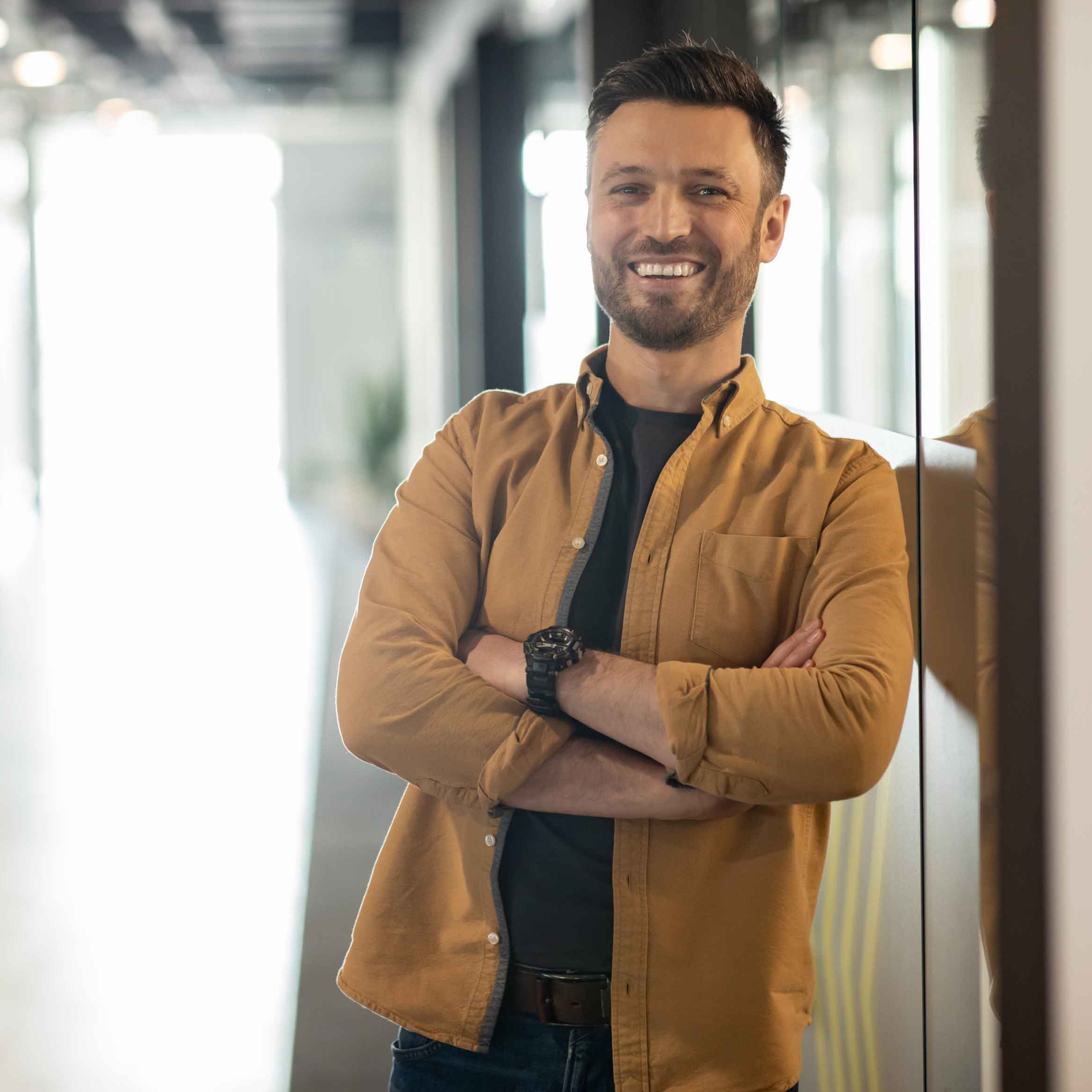Student mit braunem Hemd lacht in die Kamera